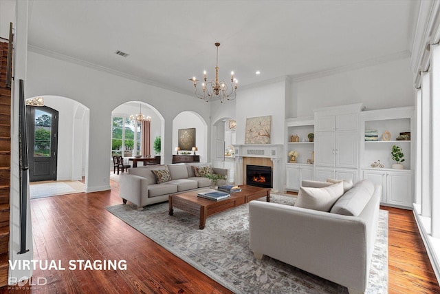 10535 Longfellow Trce, Shreveport, LA 71106 - living room with a chandelier, arched walkways, ornamental molding, wood finished floors, and a warm lit fireplace