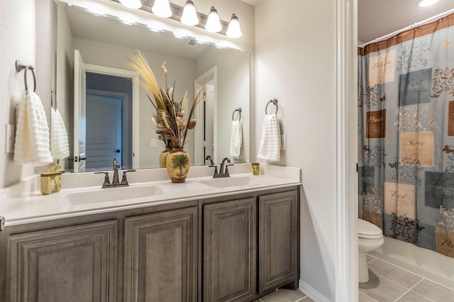 bathroom featuring double vanity, toilet, tile patterned floors, and a sink