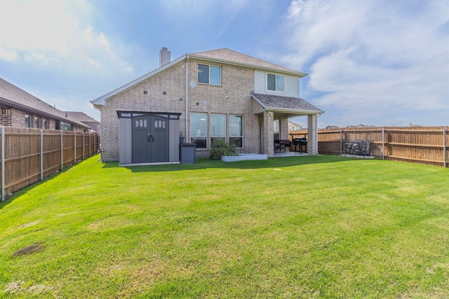 back of property with a lawn, brick siding, a chimney, and a fenced backyard