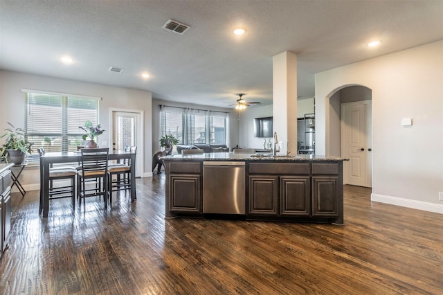 kitchen featuring dark wood-style flooring, visible vents, stainless steel dishwasher, a sink, and baseboards