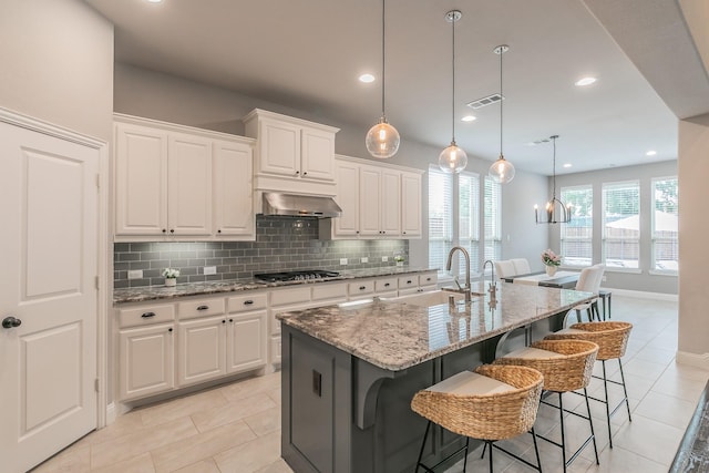 kitchen with light tile patterned floors, light stone countertops, a sink, and tasteful backsplash