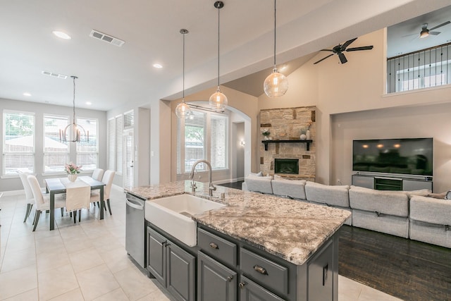 kitchen with visible vents, stainless steel dishwasher, a sink, gray cabinetry, and open floor plan