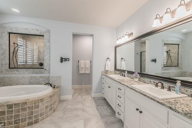 full bath with a sink, walk in shower, a garden tub, and double vanity