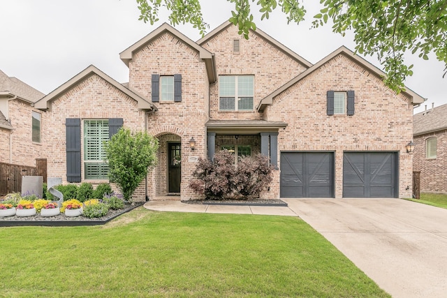 view of front of property featuring an attached garage, driveway, a front yard, and brick siding