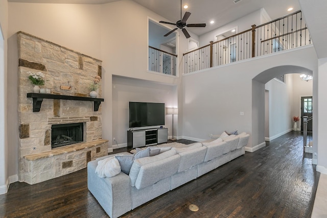 living area with arched walkways, a ceiling fan, a high ceiling, and wood finished floors