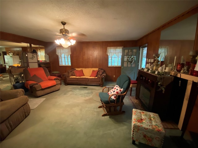 carpeted living room with wooden walls, a ceiling fan, plenty of natural light, and a fireplace