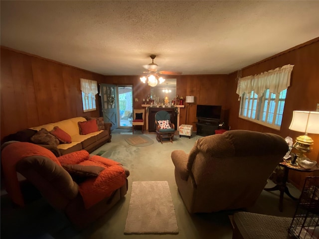 living area featuring wood walls, ceiling fan, and a healthy amount of sunlight