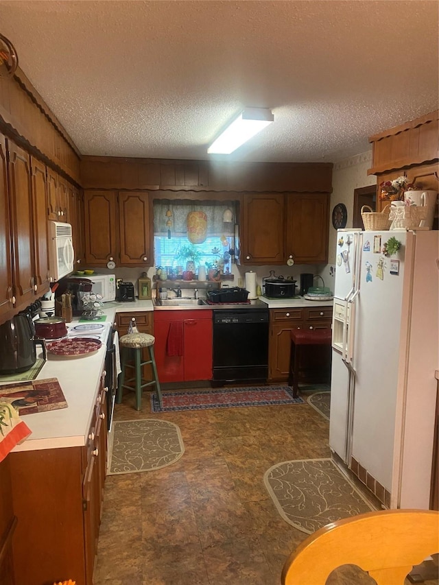kitchen with white appliances, a textured ceiling, a sink, and light countertops