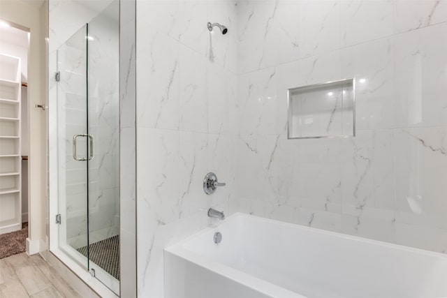 bathroom featuring a spacious closet, a bathtub, and a stall shower