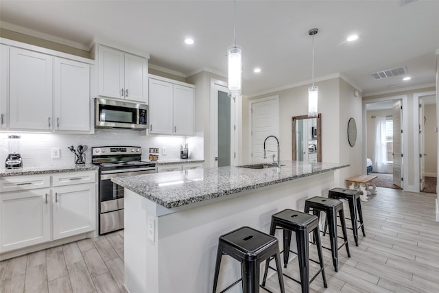 kitchen featuring a sink, appliances with stainless steel finishes, crown molding, and visible vents