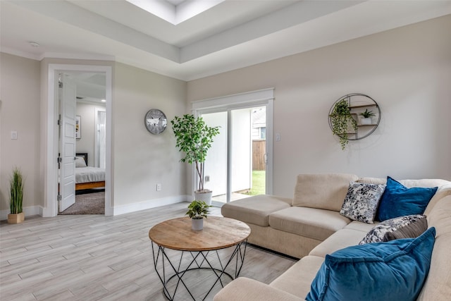 living room with baseboards, a tray ceiling, and light wood-style flooring