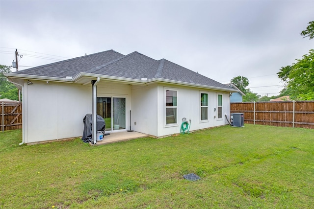 back of property featuring a lawn, central AC unit, a shingled roof, and a fenced backyard