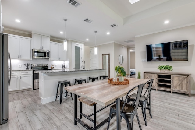 dining area with crown molding, recessed lighting, visible vents, and light wood finished floors