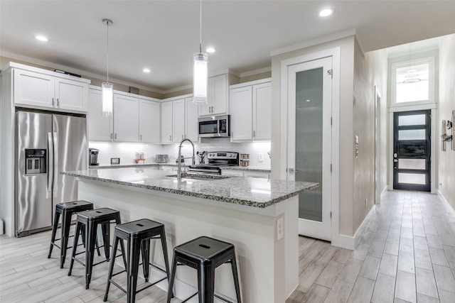 kitchen with light stone counters, tasteful backsplash, a kitchen breakfast bar, stainless steel appliances, and wood tiled floor