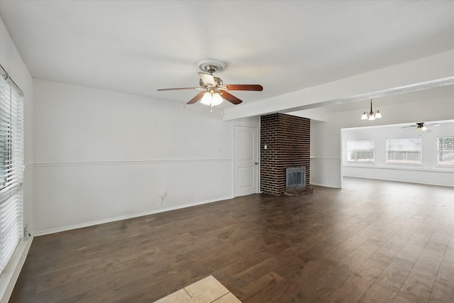 unfurnished living room with a brick fireplace, ceiling fan with notable chandelier, and wood finished floors