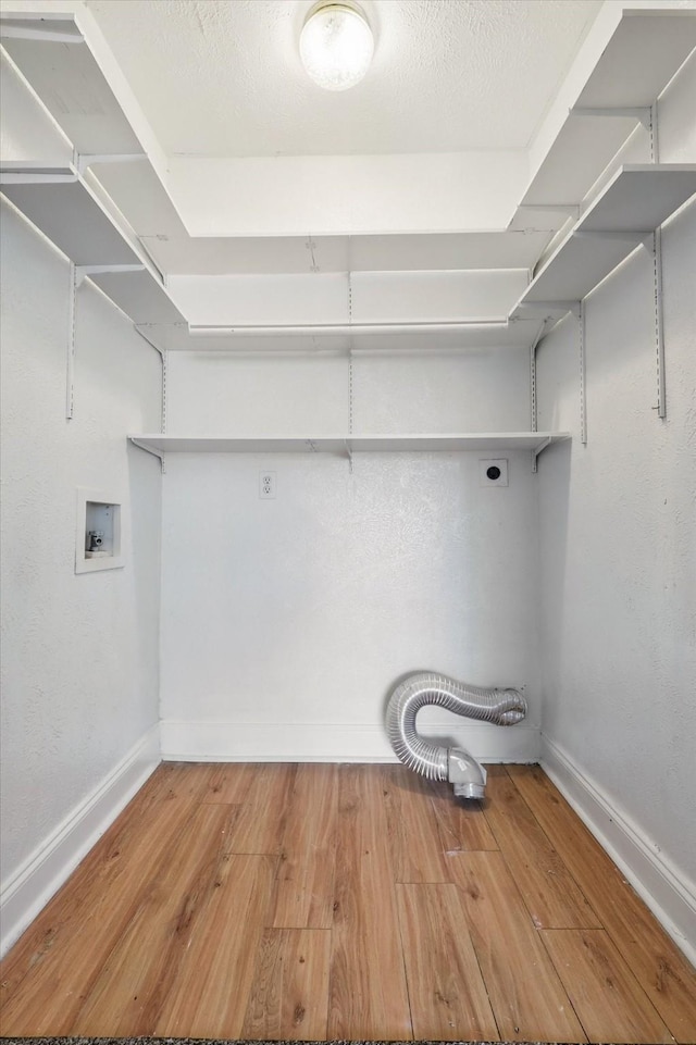 clothes washing area featuring laundry area, baseboards, washer hookup, and wood finished floors