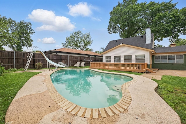 view of pool featuring a wooden deck, a water slide, a fenced backyard, a fenced in pool, and a yard