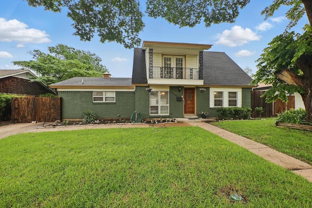 view of front of property with a shingled roof, a front lawn, fence, and a balcony
