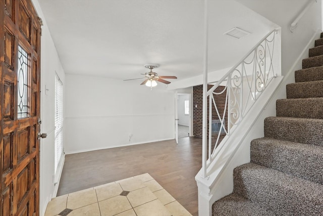 foyer entrance featuring ceiling fan, visible vents, wood finished floors, baseboards, and stairs
