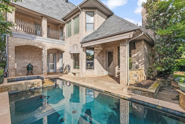 1304 Regency Ct, Southlake, TX 76092 - back of property featuring a balcony, a patio area, a pool with connected hot tub, and brick siding