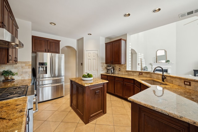 kitchen featuring a sink, visible vents, exhaust hood, arched walkways, and appliances with stainless steel finishes
