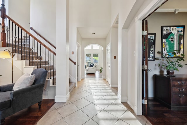 foyer with baseboards, stairs, light tile patterned flooring, and a towering ceiling