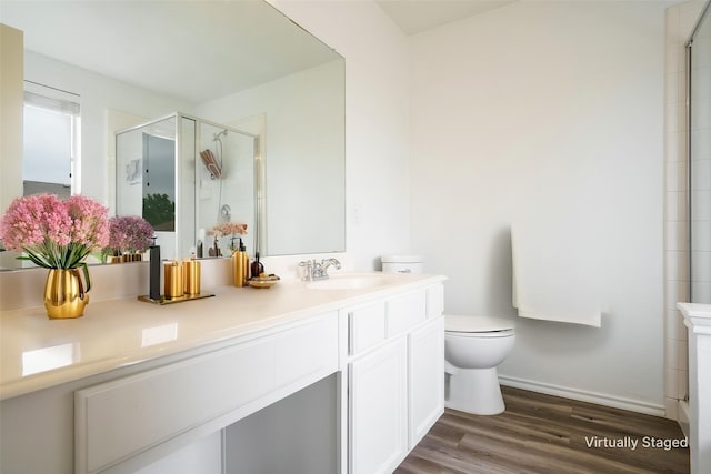 full bath with a stall shower, wood finished floors, vanity, baseboards, and toilet