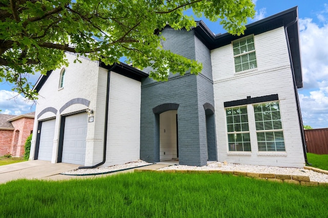 view of front of property with an attached garage, concrete driveway, a front yard, and brick siding