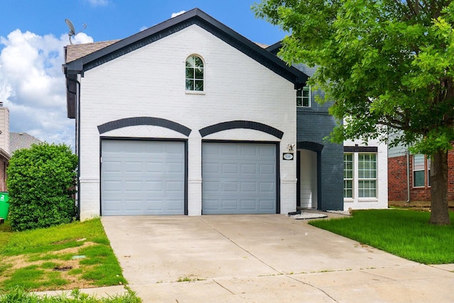 view of front of home featuring brick siding, a garage, a front lawn, and driveway