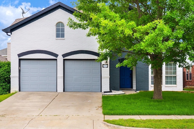 view of front facade with a garage, concrete driveway, a front lawn, and brick siding