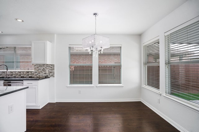 unfurnished dining area featuring an inviting chandelier, baseboards, recessed lighting, and dark wood finished floors