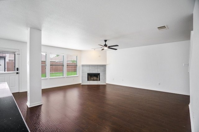 unfurnished living room featuring dark wood-style flooring, a ceiling fan, baseboards, and a fireplace