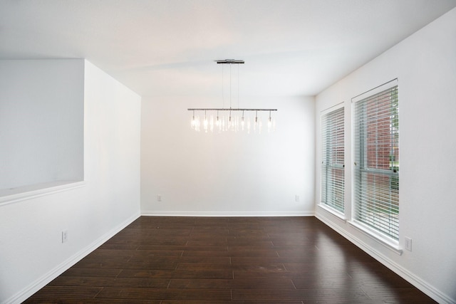 unfurnished room with baseboards, an inviting chandelier, and dark wood finished floors