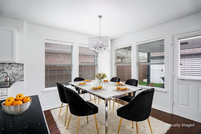 dining space featuring baseboards, dark wood-type flooring, and a notable chandelier