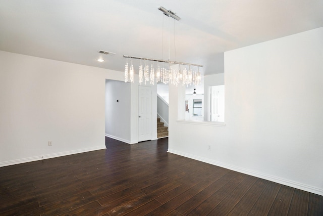 unfurnished dining area with visible vents, dark wood-style flooring, a notable chandelier, and stairway