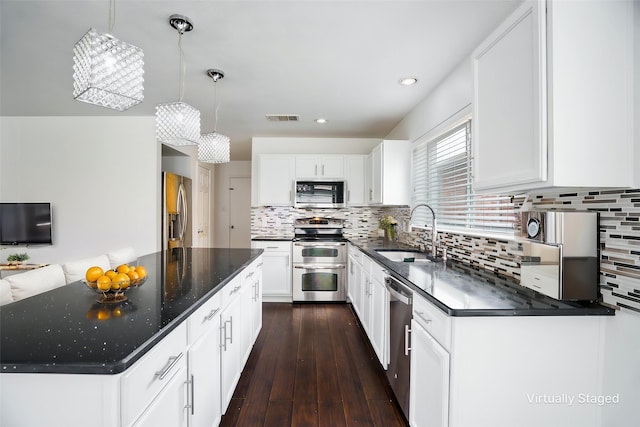 kitchen with white cabinets, appliances with stainless steel finishes, a sink, decorative backsplash, and visible vents