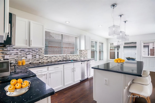 kitchen with backsplash, dishwasher, a sink, white cabinetry, and dark wood-type flooring