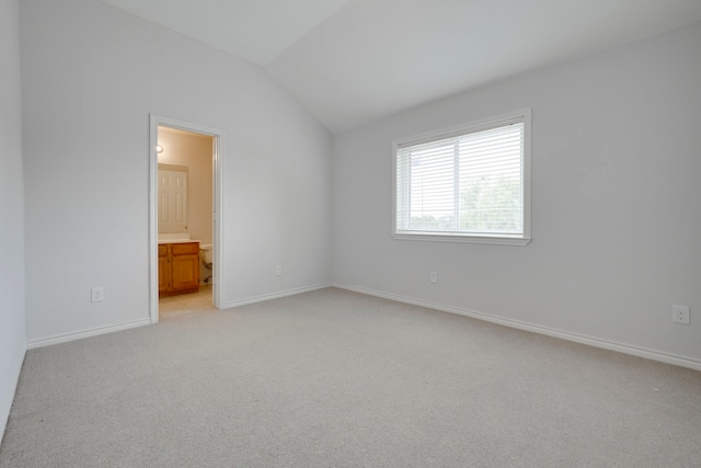 spare room with baseboards, lofted ceiling, and light carpet