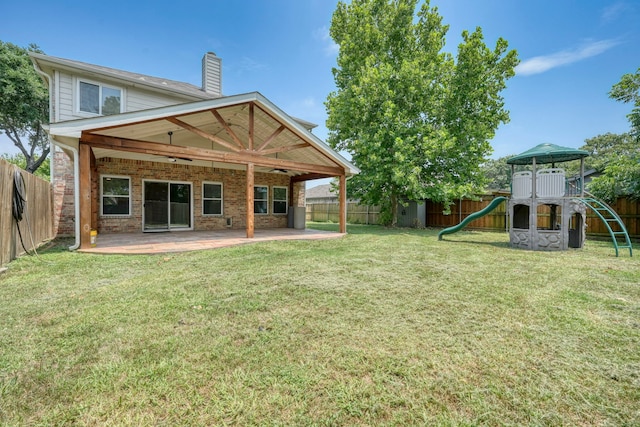 back of house featuring a chimney, a patio area, brick siding, a fenced backyard, and a playground