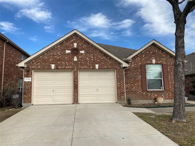 view of front of property with brick siding, driveway, and a garage