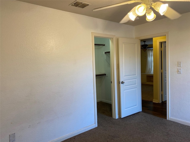 unfurnished bedroom featuring carpet flooring, a walk in closet, baseboards, visible vents, and a closet