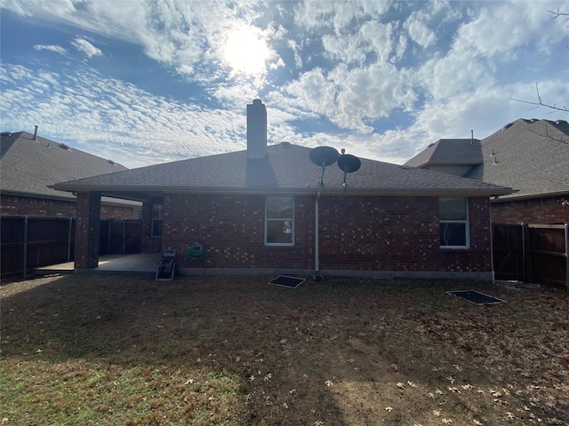 back of house with brick siding, a fenced backyard, a chimney, and a patio