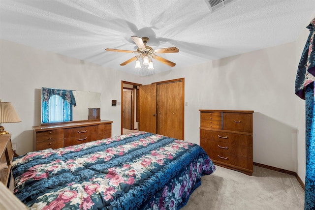 bedroom with visible vents, a closet, baseboards, ceiling fan, and light colored carpet