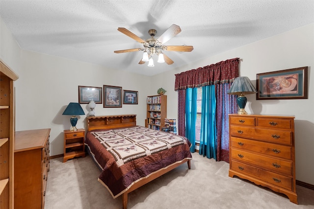 bedroom featuring a ceiling fan, a textured ceiling, and light carpet