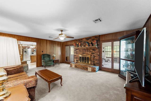 living room featuring wood walls, visible vents, ceiling fan, and carpet