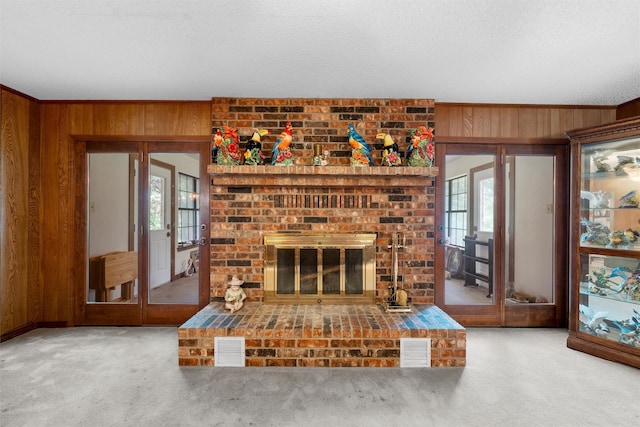 unfurnished living room with wood walls, carpet, french doors, and visible vents