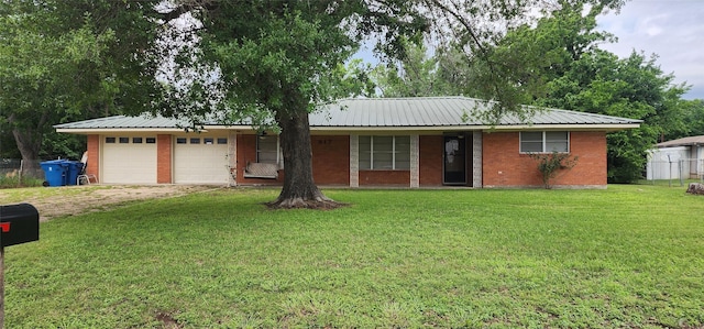 ranch-style house featuring an attached garage, dirt driveway, a front lawn, and metal roof