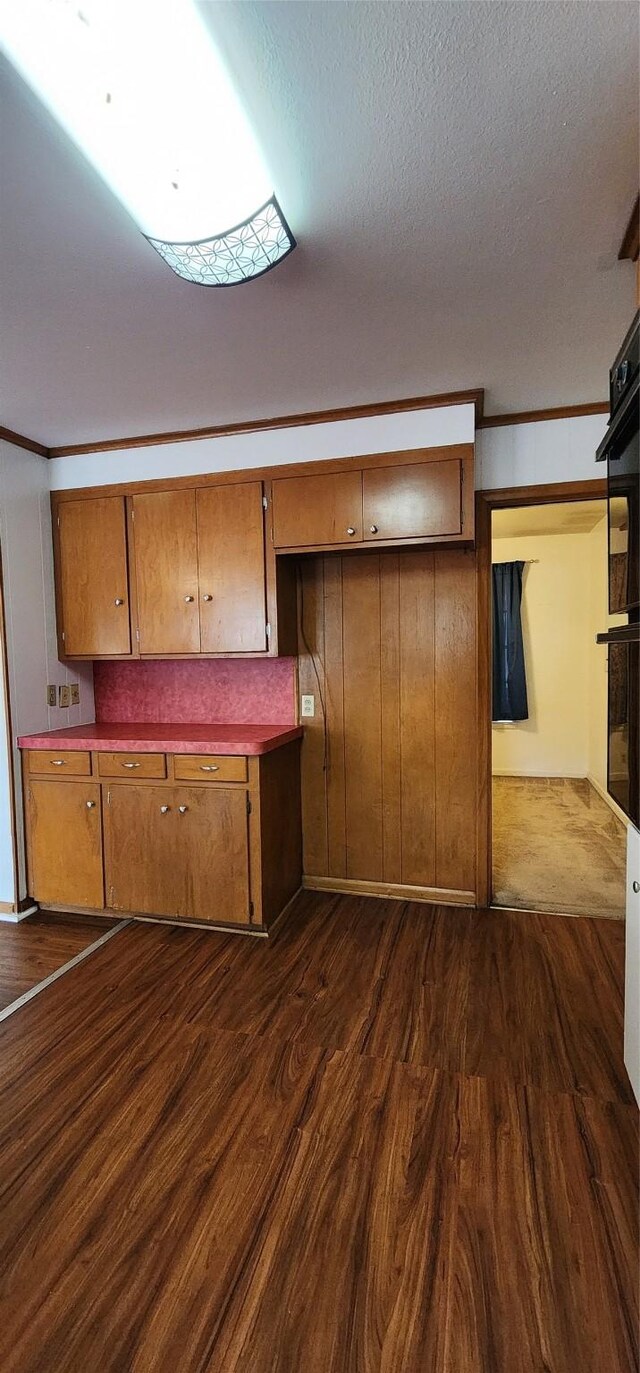 kitchen with brown cabinets, dobule oven black, dark wood-style flooring, and a textured ceiling