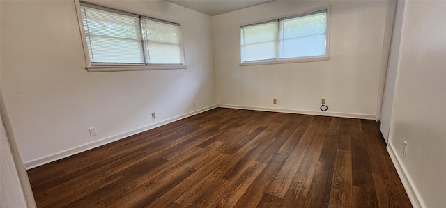 unfurnished room featuring baseboards and dark wood-type flooring