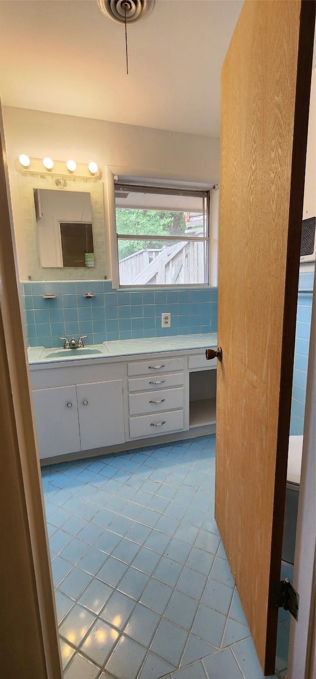 bathroom with vanity, tile patterned flooring, and tasteful backsplash